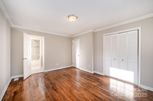 unfurnished bedroom with crown molding, ensuite bathroom, dark hardwood / wood-style floors, and a closet