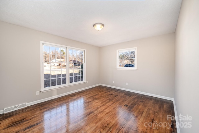 spare room with dark hardwood / wood-style floors and a textured ceiling