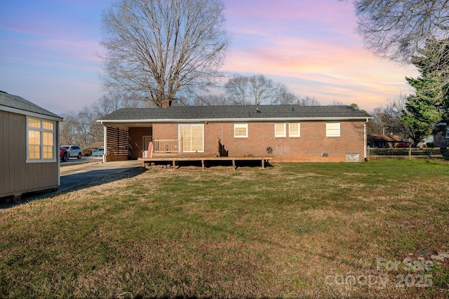 back house at dusk featuring a lawn