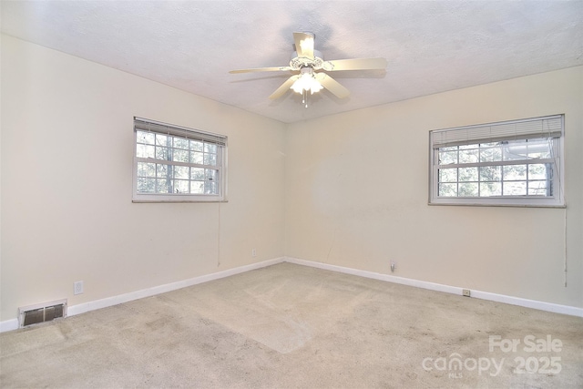 carpeted empty room with a wealth of natural light, a textured ceiling, and ceiling fan