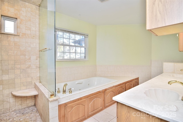 bathroom featuring vanity, a relaxing tiled tub, tile patterned floors, and tile walls