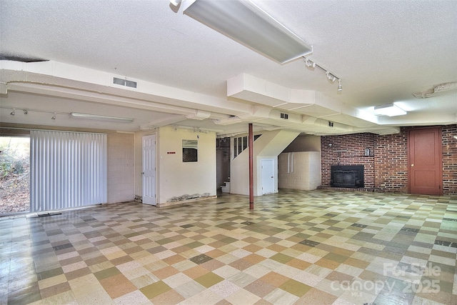 basement featuring a fireplace, brick wall, and a textured ceiling