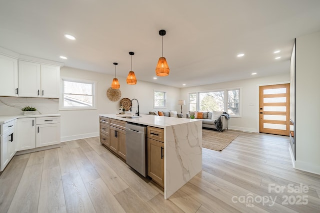 kitchen with white cabinets, light stone counters, sink, dishwasher, and hanging light fixtures