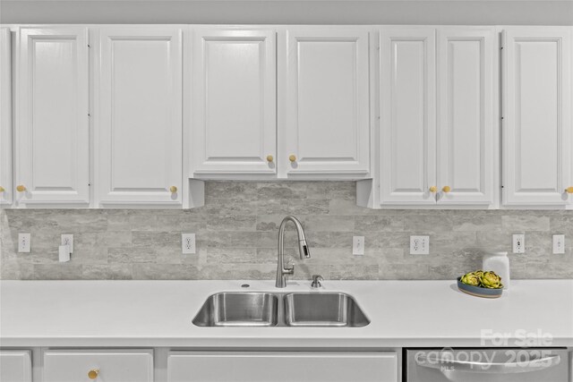 kitchen featuring backsplash, sink, white cabinetry, and stainless steel dishwasher