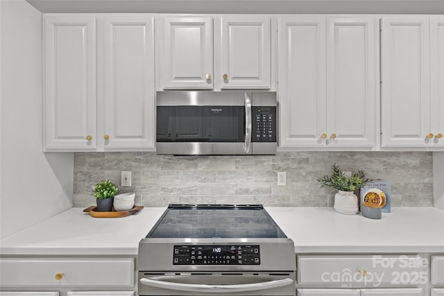 kitchen with decorative backsplash, white cabinets, and stainless steel appliances