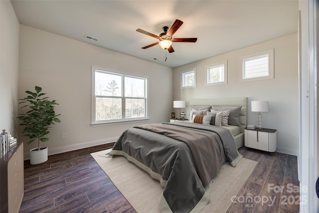 bedroom with a ceiling fan, visible vents, baseboards, and wood finished floors