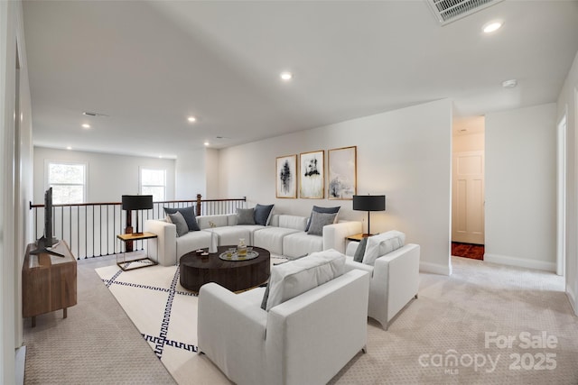 living area featuring recessed lighting, visible vents, baseboards, and light colored carpet