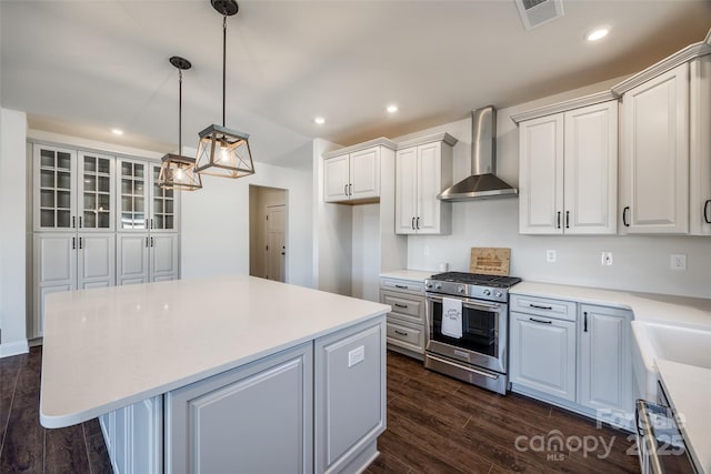 kitchen with visible vents, dark wood finished floors, gas range, a center island, and wall chimney range hood