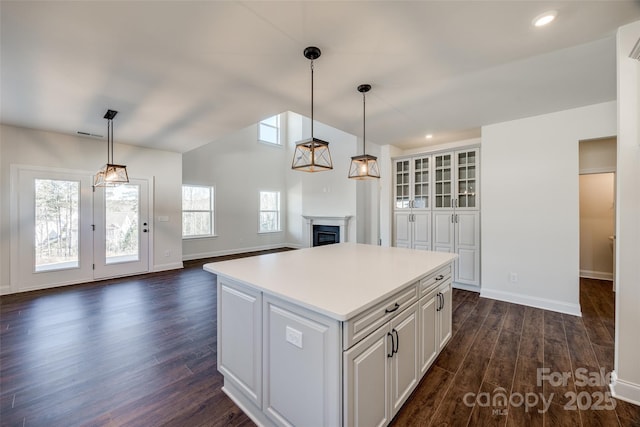 kitchen with white cabinets, dark wood-style floors, open floor plan, light countertops, and pendant lighting