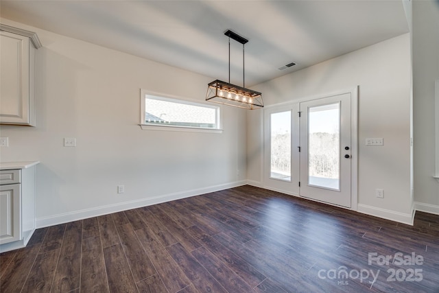 unfurnished dining area with dark wood-type flooring, visible vents, and baseboards