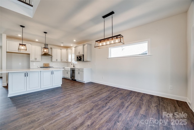 kitchen featuring baseboards, dark wood finished floors, wall chimney exhaust hood, appliances with stainless steel finishes, and light countertops