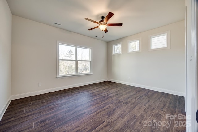 empty room with dark wood-type flooring, visible vents, baseboards, and a ceiling fan