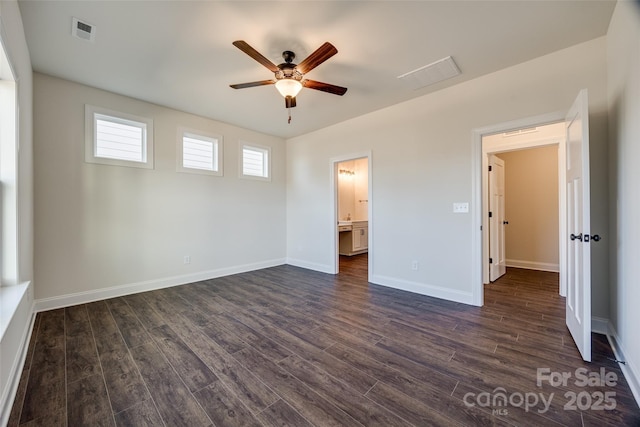 unfurnished bedroom with dark wood-style floors, visible vents, baseboards, and ensuite bathroom