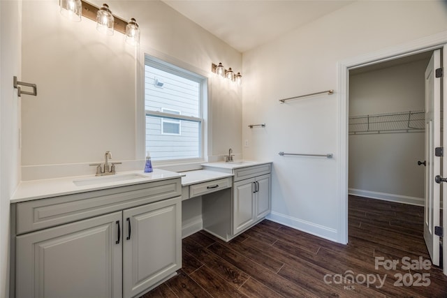 full bathroom featuring two vanities, a sink, baseboards, and wood finished floors