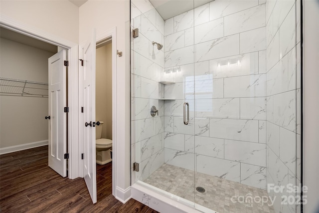 full bathroom with toilet, a shower stall, baseboards, and wood finished floors