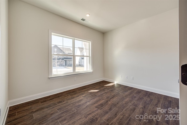 spare room with baseboards, visible vents, and dark wood-type flooring