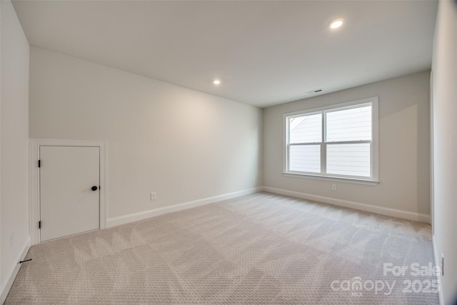 empty room with recessed lighting, light colored carpet, visible vents, and baseboards