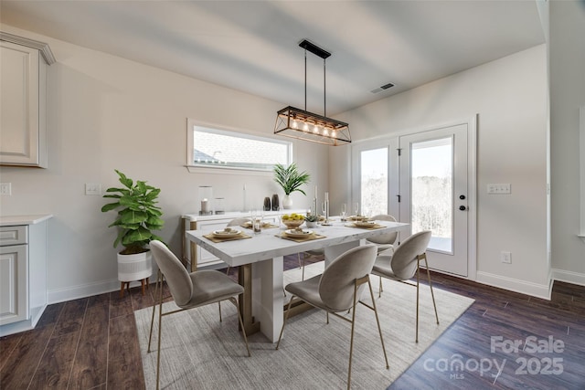 dining space with baseboards, visible vents, and wood finished floors