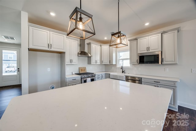 kitchen with recessed lighting, stainless steel appliances, dark wood-style flooring, a sink, and wall chimney exhaust hood