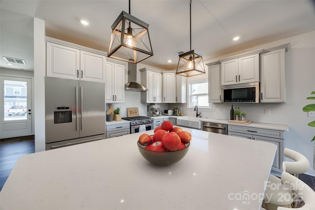 kitchen with recessed lighting, visible vents, appliances with stainless steel finishes, a sink, and wall chimney exhaust hood