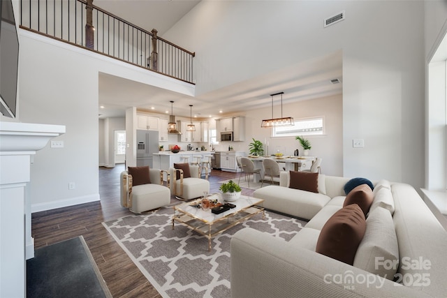 living area featuring dark wood-style floors, a wealth of natural light, a high ceiling, and visible vents