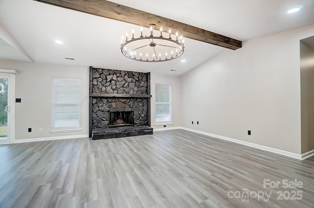 unfurnished living room featuring wood-type flooring, vaulted ceiling with beams, a fireplace, and a wealth of natural light