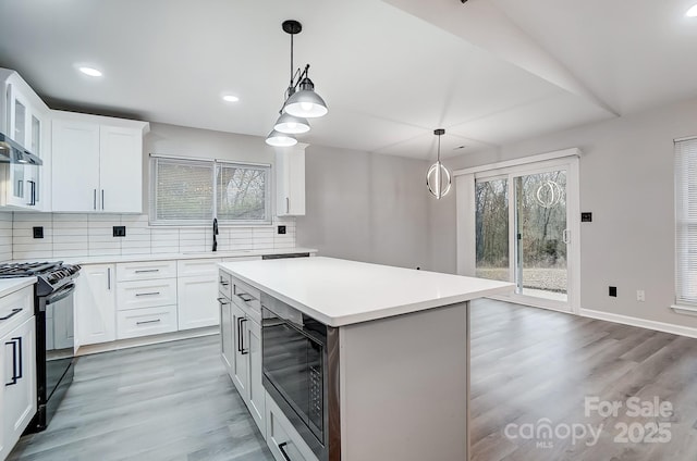 kitchen featuring black range oven, white cabinetry, a center island, tasteful backsplash, and built in microwave