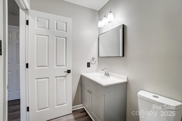 bathroom with hardwood / wood-style flooring, vanity, and toilet