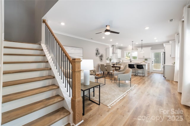 stairway featuring hardwood / wood-style floors, ceiling fan, and ornamental molding