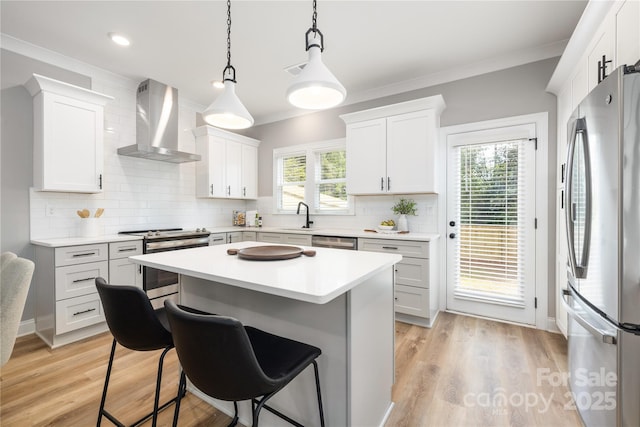 kitchen featuring white cabinetry, stainless steel appliances, and wall chimney range hood