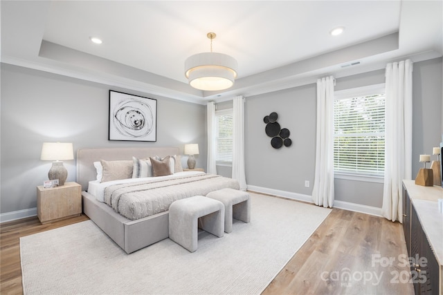 bedroom with hardwood / wood-style floors and a tray ceiling