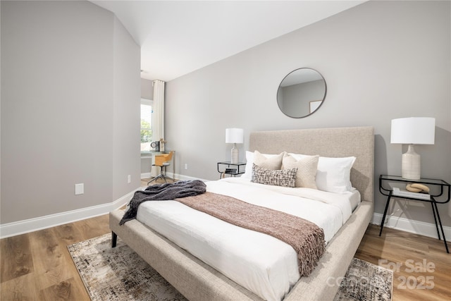 bedroom with lofted ceiling and wood-type flooring