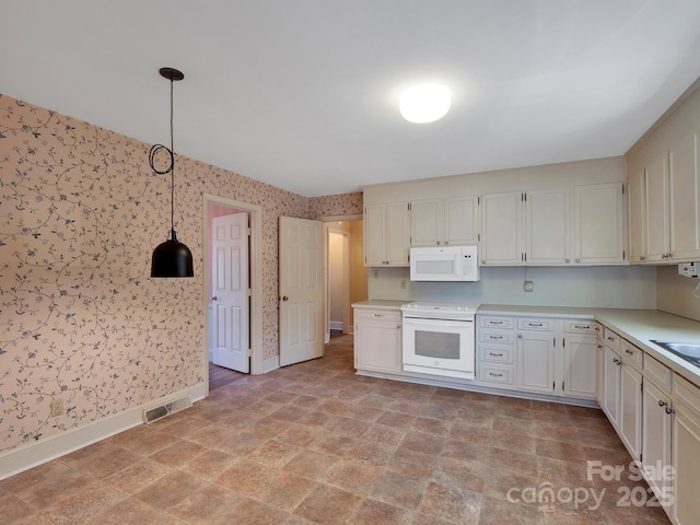 kitchen featuring white cabinetry, sink, decorative light fixtures, and white appliances