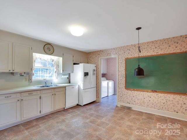 kitchen featuring washer / clothes dryer, sink, pendant lighting, and white appliances