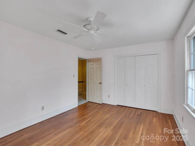 unfurnished bedroom featuring hardwood / wood-style floors, a closet, and ceiling fan