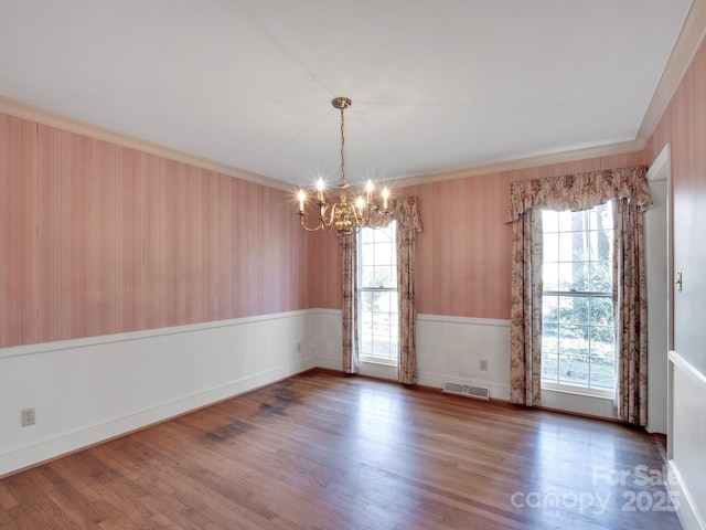 empty room featuring ornamental molding, a healthy amount of sunlight, dark hardwood / wood-style floors, and a notable chandelier