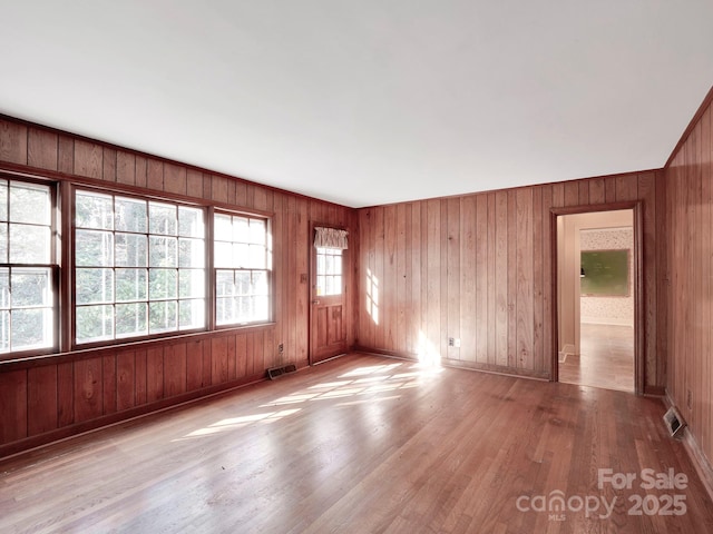 spare room featuring wood walls and light hardwood / wood-style floors