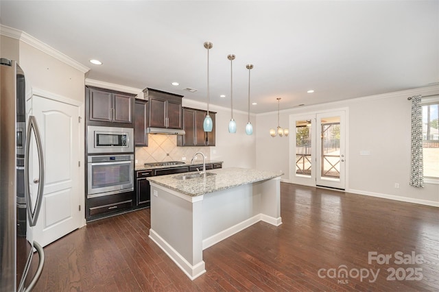 kitchen featuring light stone countertops, a kitchen island with sink, sink, pendant lighting, and stainless steel appliances