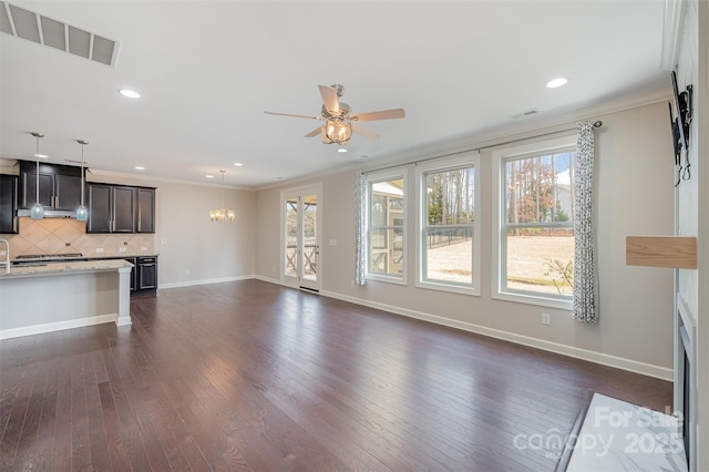 unfurnished living room featuring dark wood-type flooring, ceiling fan with notable chandelier, and ornamental molding