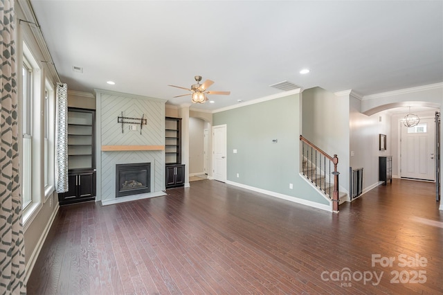 unfurnished living room with a large fireplace, ornamental molding, dark hardwood / wood-style flooring, built in features, and ceiling fan