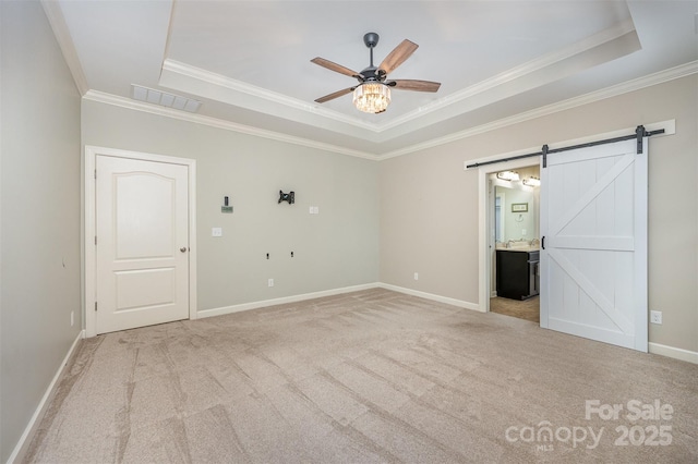 carpeted spare room featuring crown molding, a raised ceiling, ceiling fan, and a barn door