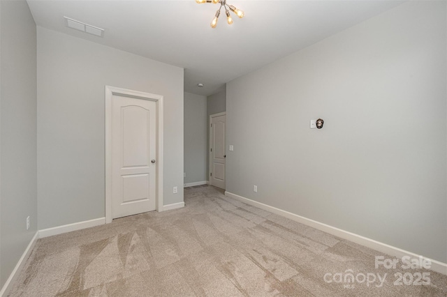 carpeted empty room featuring an inviting chandelier