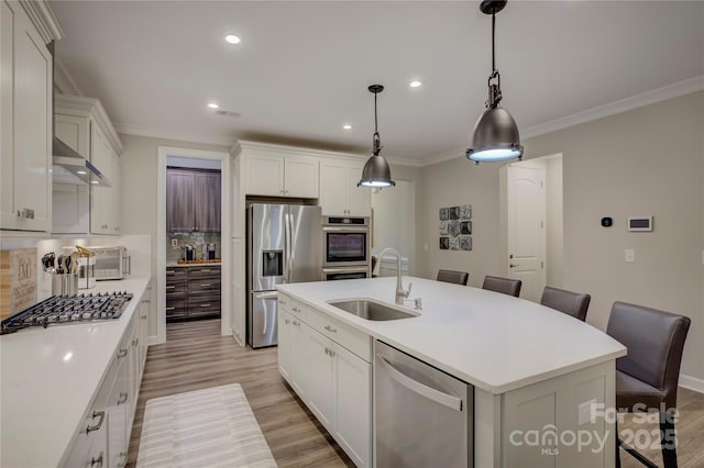 kitchen with white cabinets, sink, an island with sink, appliances with stainless steel finishes, and decorative light fixtures