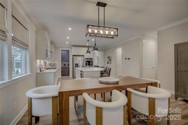 dining room featuring light wood-type flooring, crown molding, and sink