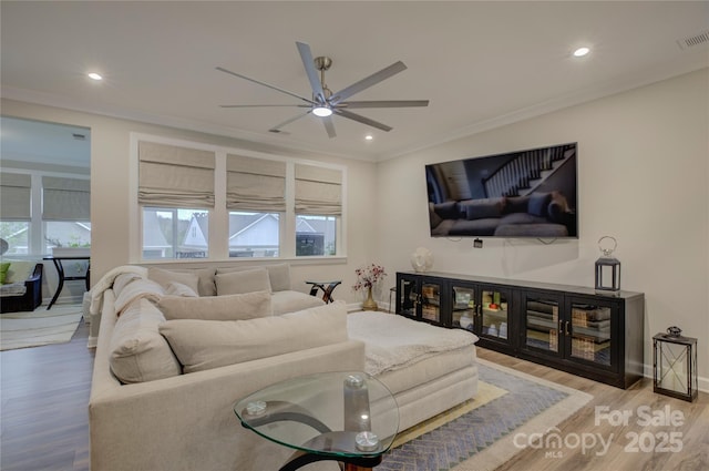 living room featuring light wood-type flooring, ceiling fan, and ornamental molding