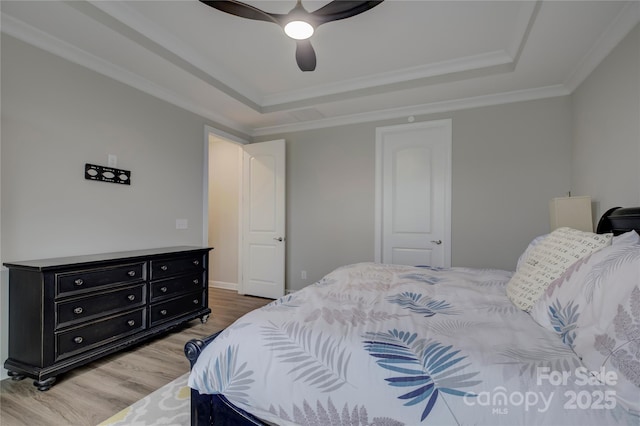 bedroom featuring wood-type flooring, a raised ceiling, ceiling fan, and crown molding