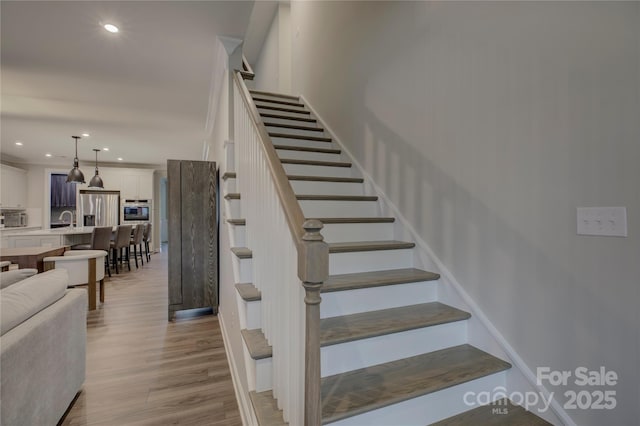 staircase featuring hardwood / wood-style floors and sink