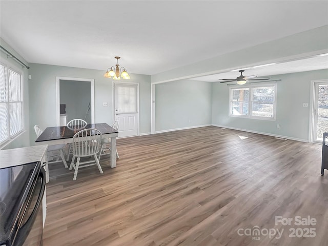 dining room featuring a healthy amount of sunlight, wood-type flooring, and ceiling fan with notable chandelier