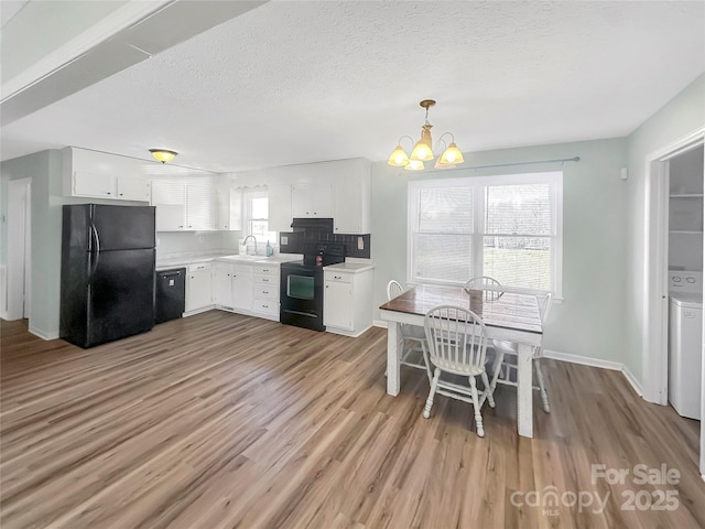 kitchen with black appliances, decorative light fixtures, white cabinetry, and sink