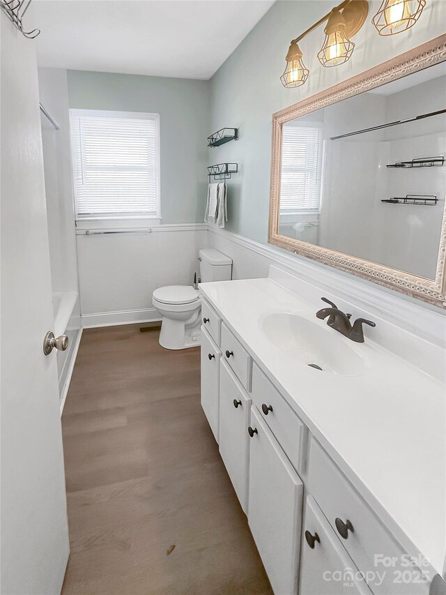 full bathroom with wood-type flooring, vanity, toilet, and a healthy amount of sunlight